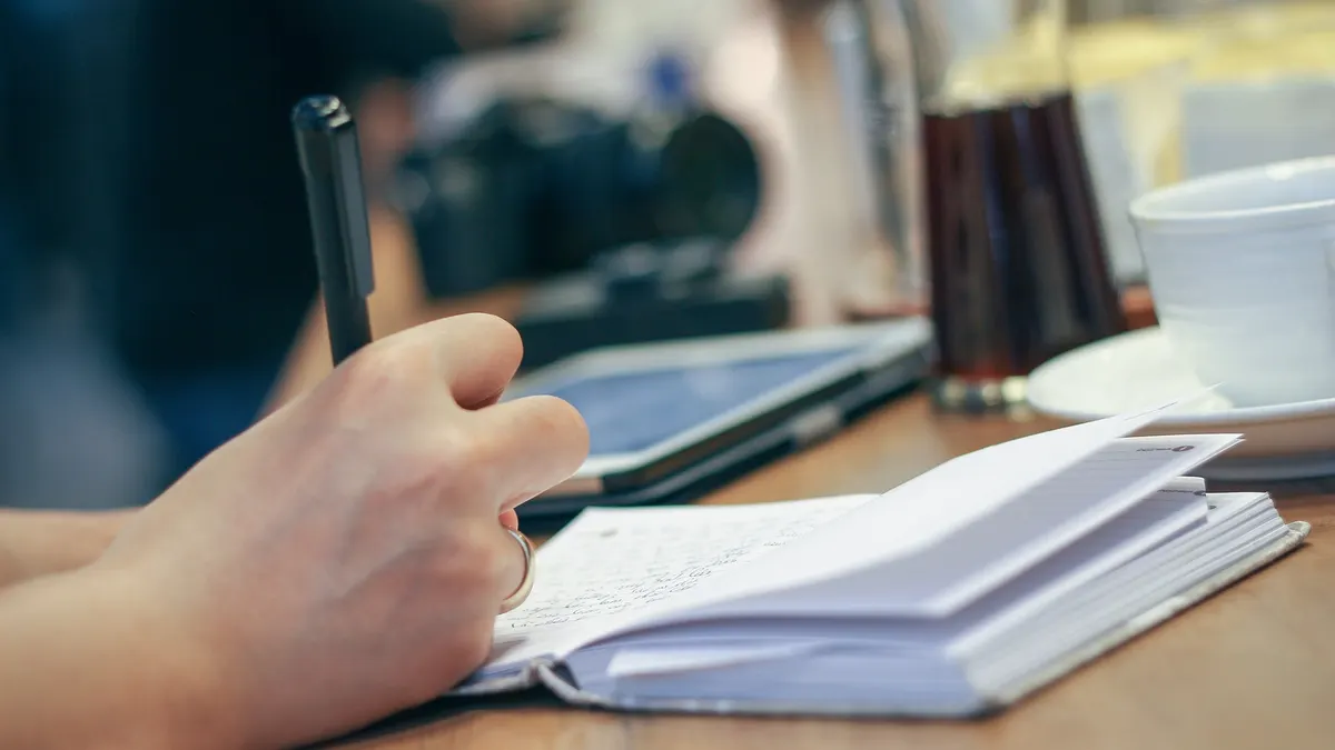 Hand writing in a notebook at a desk